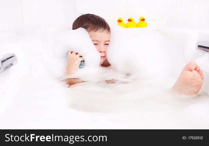 Cute four year old boy taking a relaxing bath with foam. Cute four year old boy taking a relaxing bath with foam