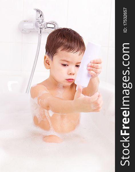 Cute four year old boy taking a relaxing bath with foam and using cosmetics. Cute four year old boy taking a relaxing bath with foam and using cosmetics