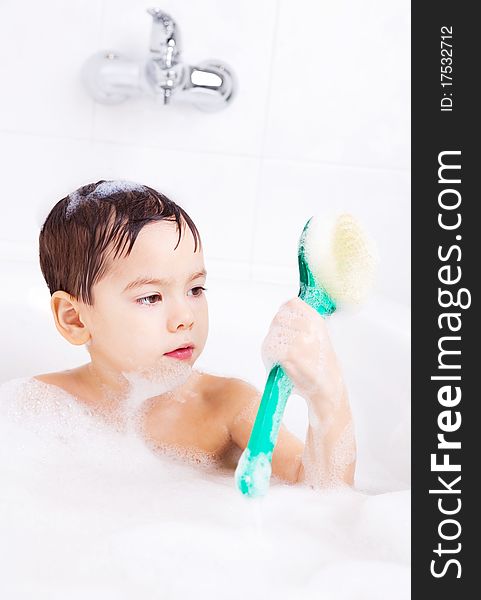 Cute four year old boy taking a relaxing bath with foam and using a brush. Cute four year old boy taking a relaxing bath with foam and using a brush