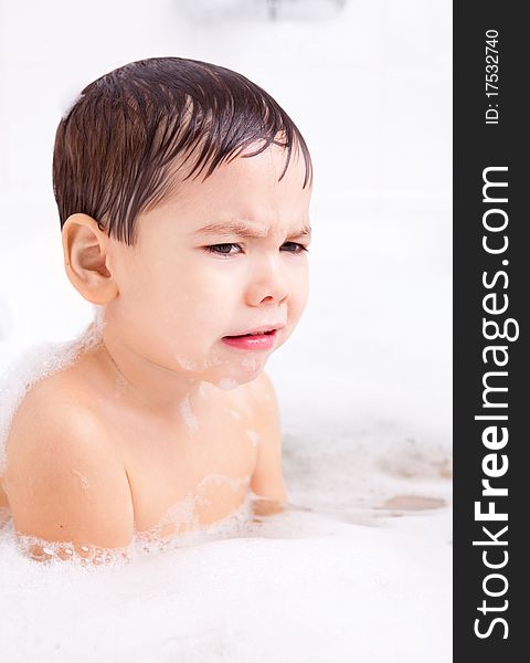 Displeased unhappy four year old boy taking a bath with foam. Displeased unhappy four year old boy taking a bath with foam