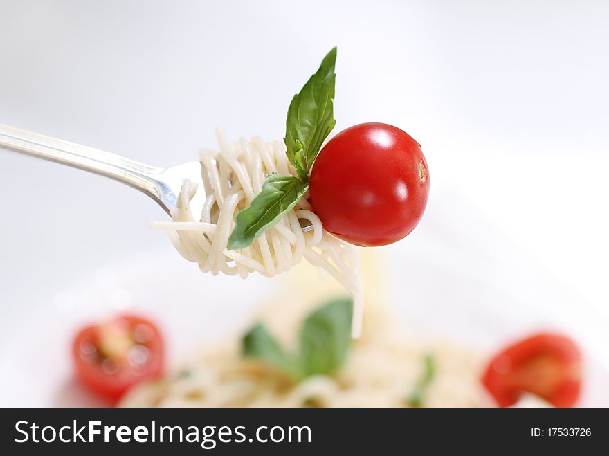 Spaghetti, basil and tomato on fork