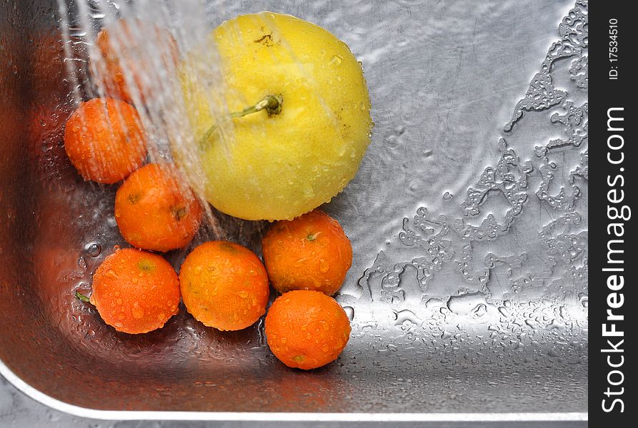 Citrus fruits in a kitchen sink are being washed. Citrus fruits in a kitchen sink are being washed