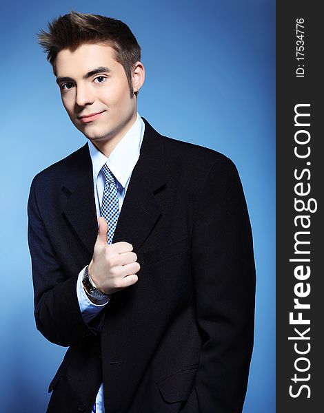 Portrait of a young businessman posing over grey background.