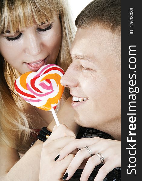 The young couple licking lollypop shape of heart. The young couple licking lollypop shape of heart