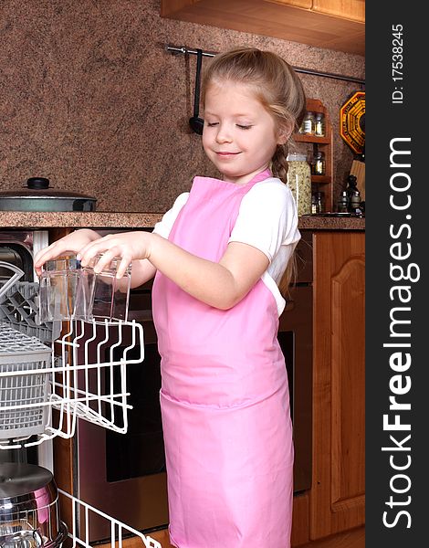 Little girl taken clear glass from dishwasher in the kitchen