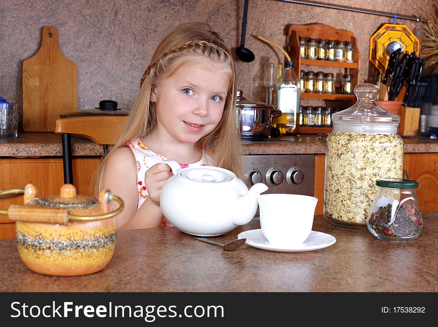 Little girl breakfast with teapot and cup of hot drink in the kitchen. Little girl breakfast with teapot and cup of hot drink in the kitchen