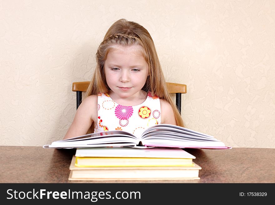 Little girl reading book against yellow wall at home