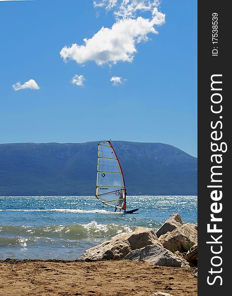 Surfer on the blue sea with island and blue sky in background