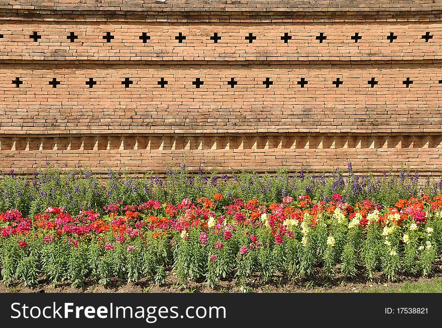 Brown brick wall.Flower garden