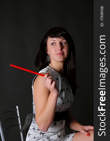 Brunette on a dark background with a red pencil. Brunette on a dark background with a red pencil