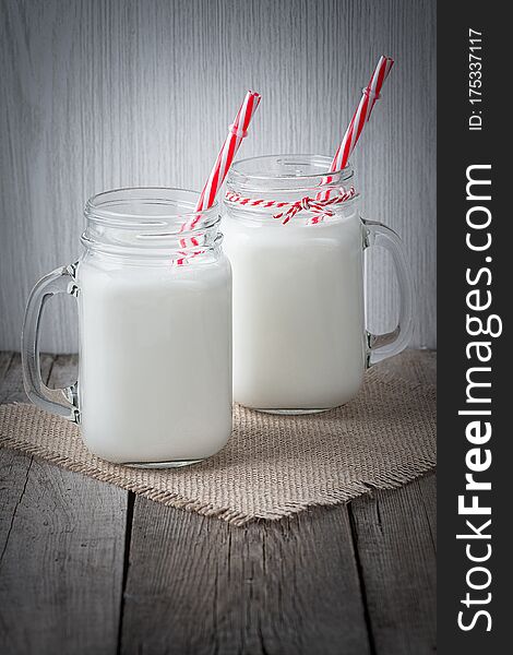 Glass cups with milk on a wooden rustic background.