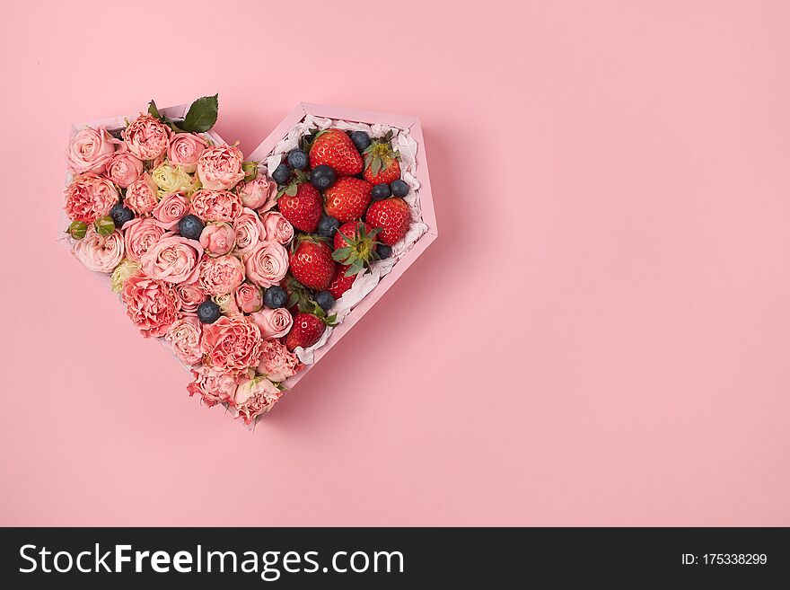 Wooden Box In The Heart Shape Filled With Roses And Ripe Strawberries On A Pink Background