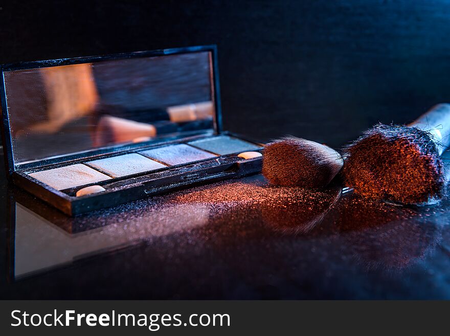 Makeup set with brushes and dust on dark background.