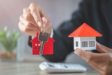 Real Estate Agent Holding House Model And Keys,  Customer Signing Contract To Buy House, Insurance Or Loan Real Estate Stock Photo