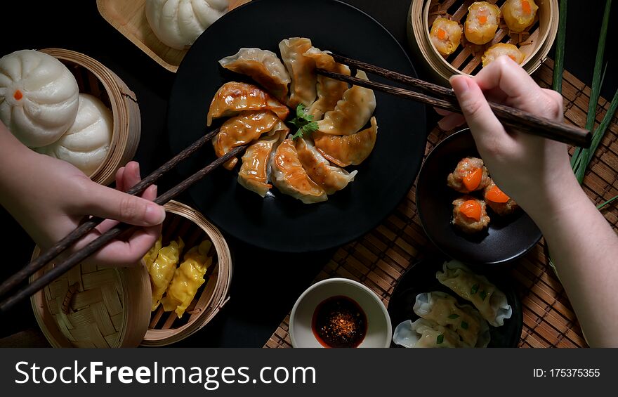 Top view of two female eating Dim sum with fried Japanese Gyoza dumplings, Chinese dumplings, salted egg pork balls and buns in Chinese restaurant. Top view of two female eating Dim sum with fried Japanese Gyoza dumplings, Chinese dumplings, salted egg pork balls and buns in Chinese restaurant