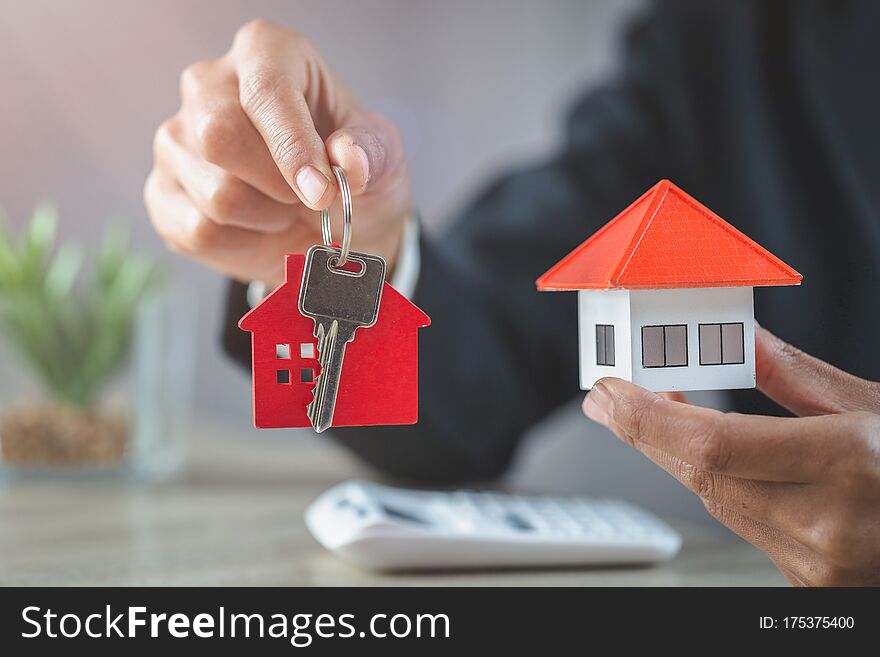 Real estate agent holding house model and keys,  customer signing contract to buy house, insurance or loan real estate.