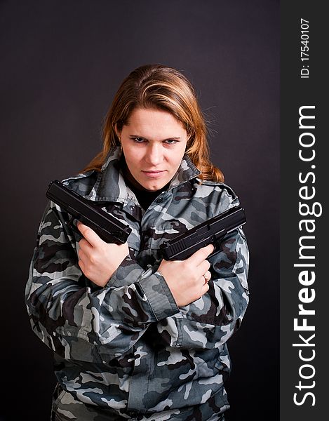 Girl in a camouflage clothing holding guns. Girl in a camouflage clothing holding guns
