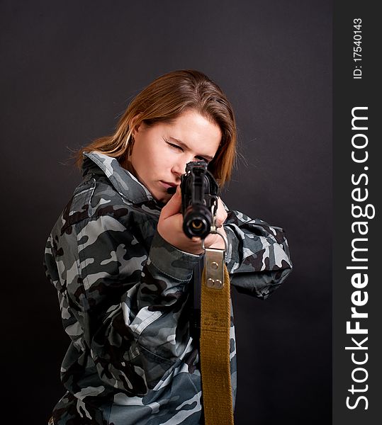 Girl in a camouflage clothing holding gun. Girl in a camouflage clothing holding gun