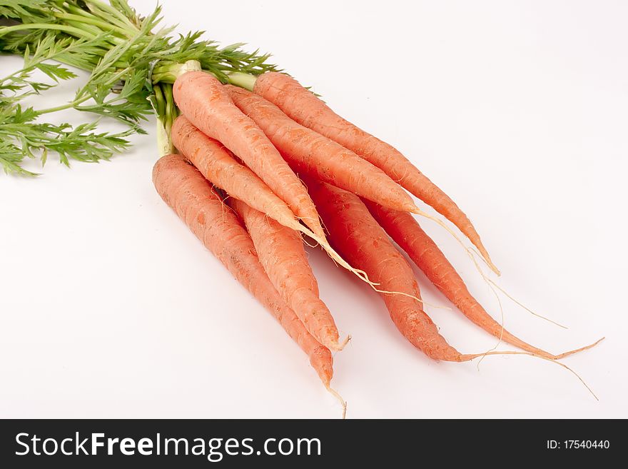 A beam of young carrots with green tops on white background. A beam of young carrots with green tops on white background.