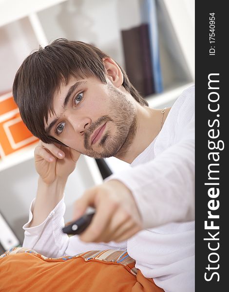 Young man with remote control watching television