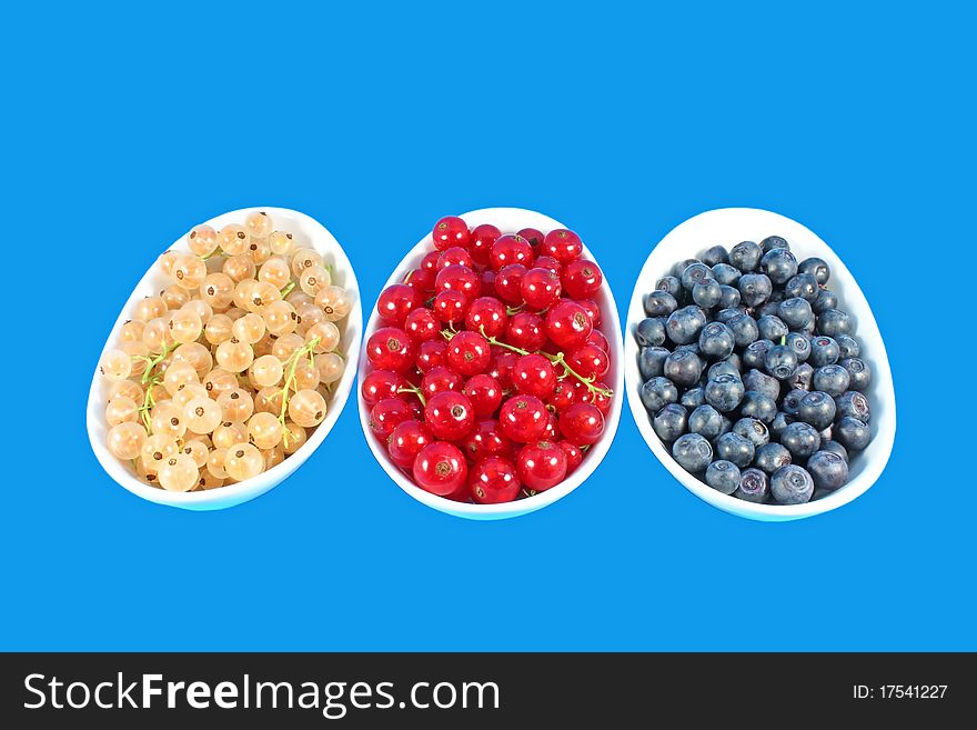 Three white bowls full of colorful berries isolated on blue
