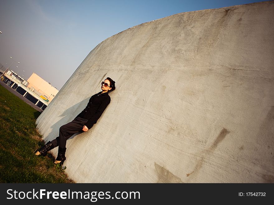 The woman is leaning on a circular wall