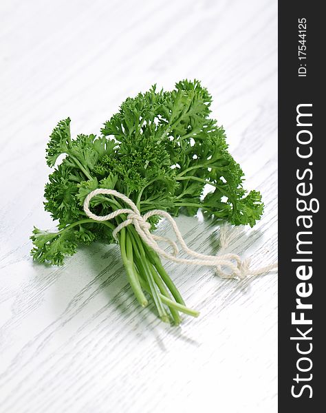 Parsley herb leaves tied in over the white wooden background