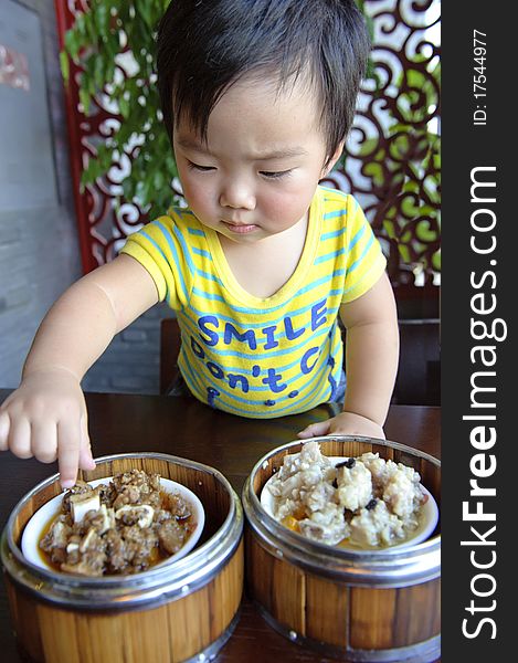 A cute baby is eating in a restaurant. A cute baby is eating in a restaurant