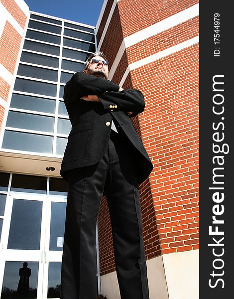 Attractive 40 year old business man in suit and sunglasses walking standing arms crossed serious office building. Attractive 40 year old business man in suit and sunglasses walking standing arms crossed serious office building.