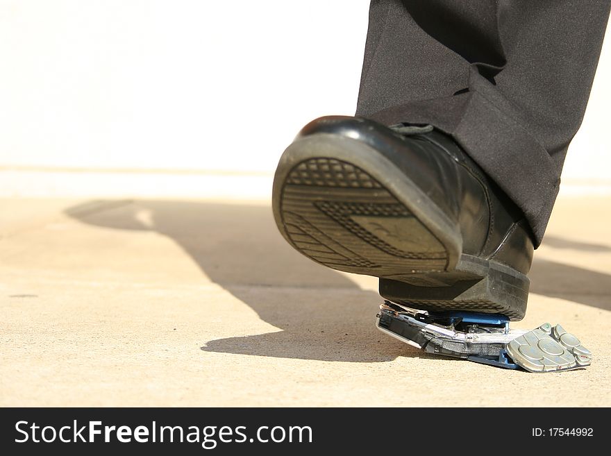 Man heel stepping on broken cellphone on sidewalk. Man heel stepping on broken cellphone on sidewalk.