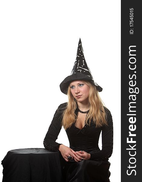 A young woman in a witch costume sit near the table