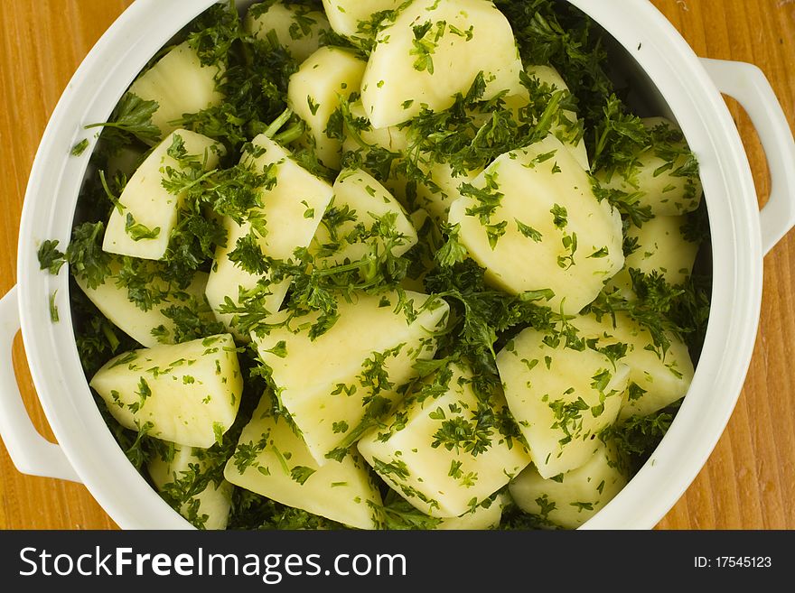Raw uncooked potato pieces halved  and garnished with fresh parsley in a white bowl. Raw uncooked potato pieces halved  and garnished with fresh parsley in a white bowl