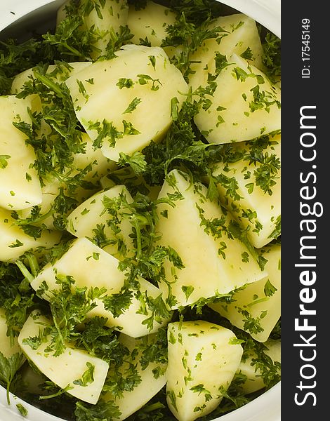 Raw uncooked potato pieces halved  and garnished with fresh parsley in a white bowl. Raw uncooked potato pieces halved  and garnished with fresh parsley in a white bowl