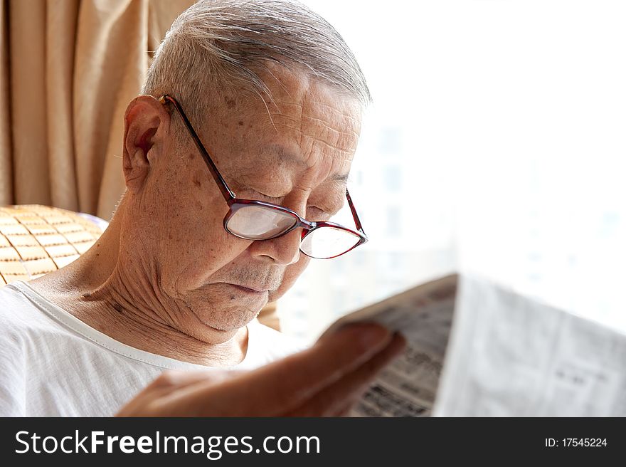 A senior man is reading newspaper