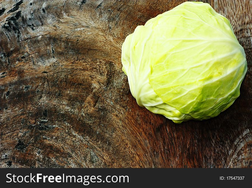 Green cabbage on wooden chopping board