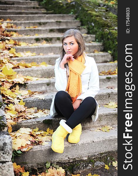 Adorable woman sitting on stairs in autumn park