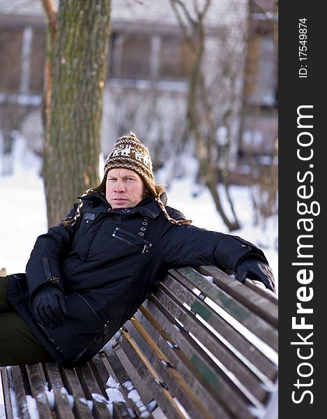 Portrait of adult man on bench in winter time