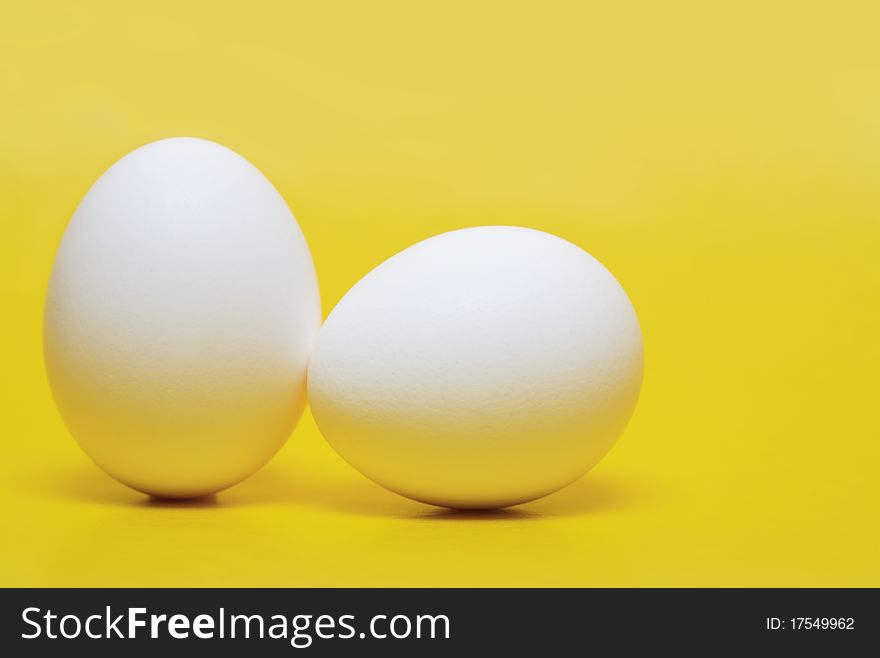 Two white hen's eggs isolated on yellow background. Two white hen's eggs isolated on yellow background
