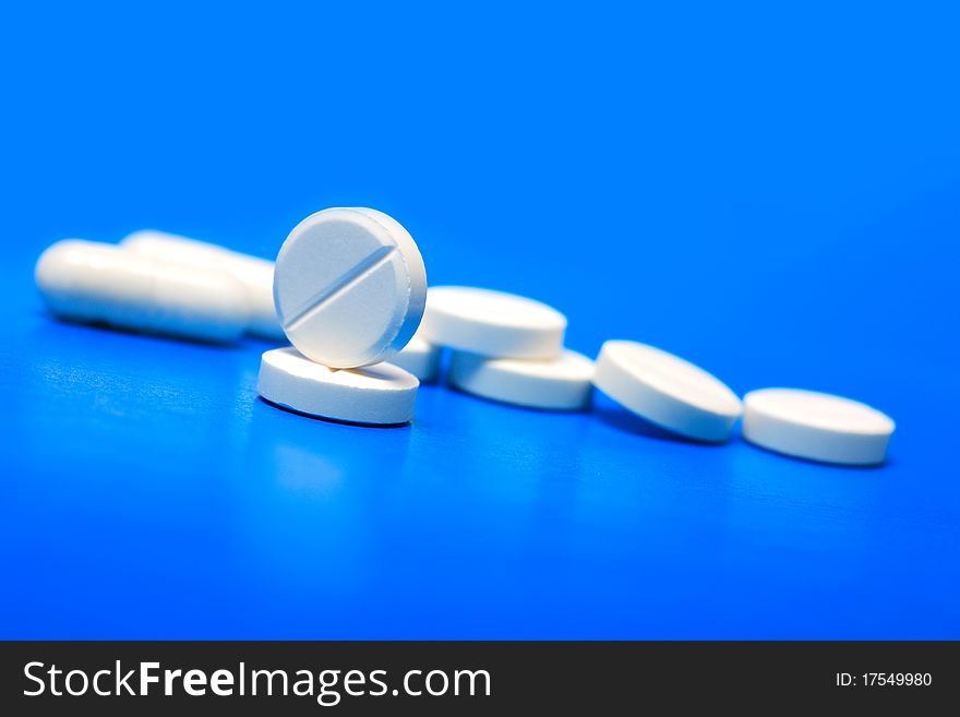 Extreme closeup of few pills on blue background with copy space