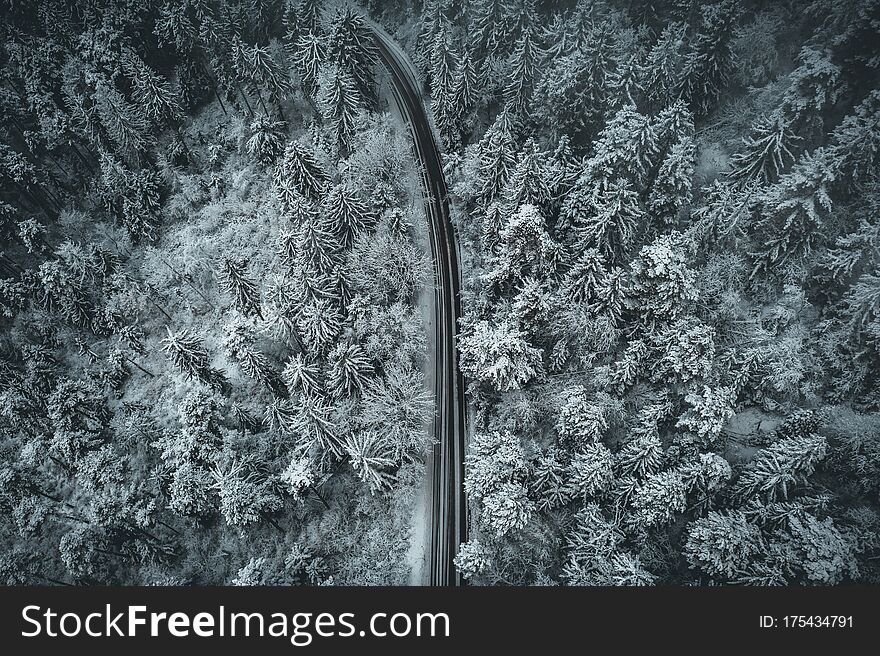 Snowy and frozen winter road aerial view in the forest