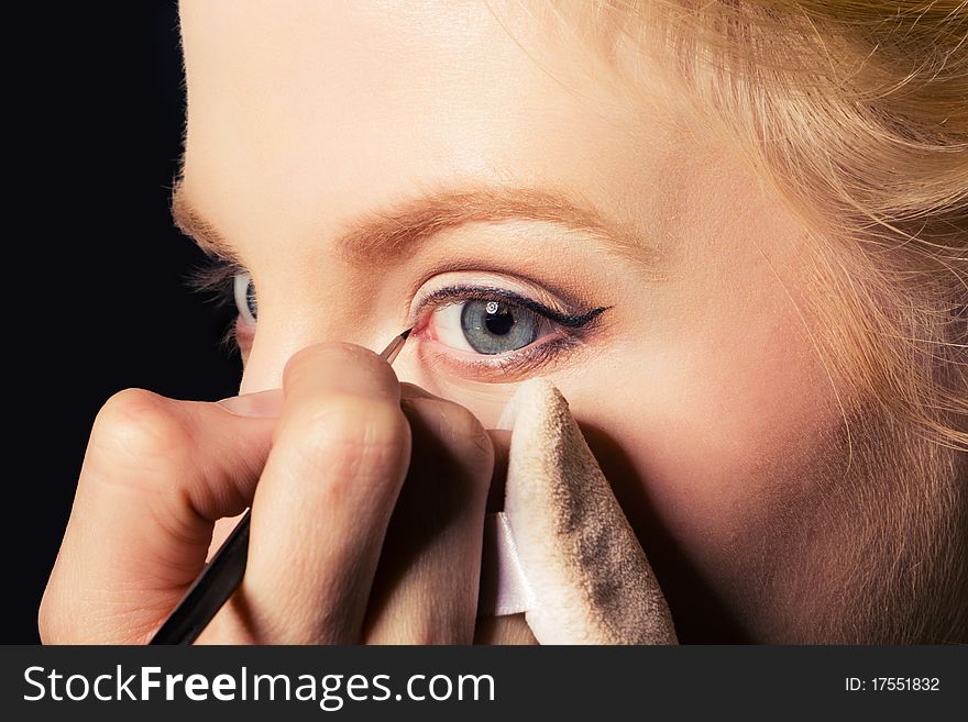 Charming young woman applying blusher eyelid. Close-up view.