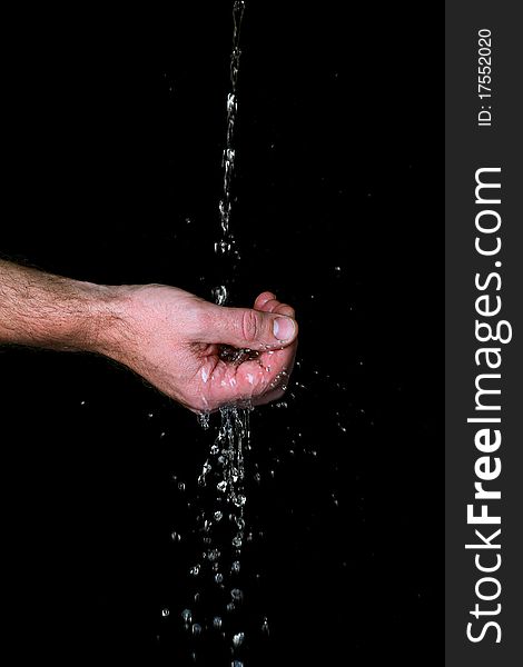 Water runs trough the fingers, against black background