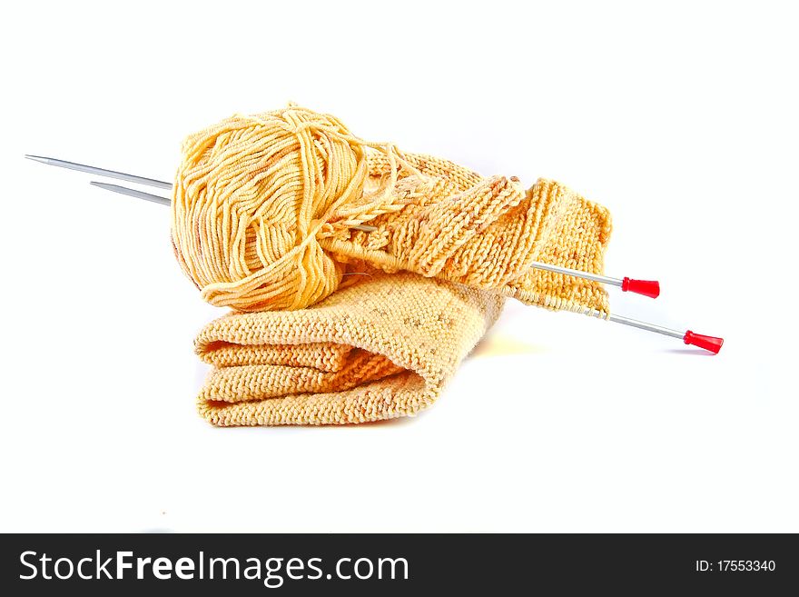 Knitting yarn and needles rest on top of a knitting project, isolated. Horizontal