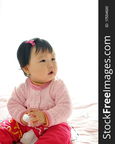 A Asian baby girl sitting on the bed