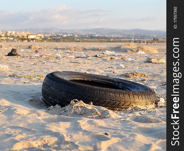 Garbage thrown on the shore by the sea after a storm; in this picture a car wheel appears as the main subject due to its more pronounced detail among other objects. Garbage thrown on the shore by the sea after a storm; in this picture a car wheel appears as the main subject due to its more pronounced detail among other objects