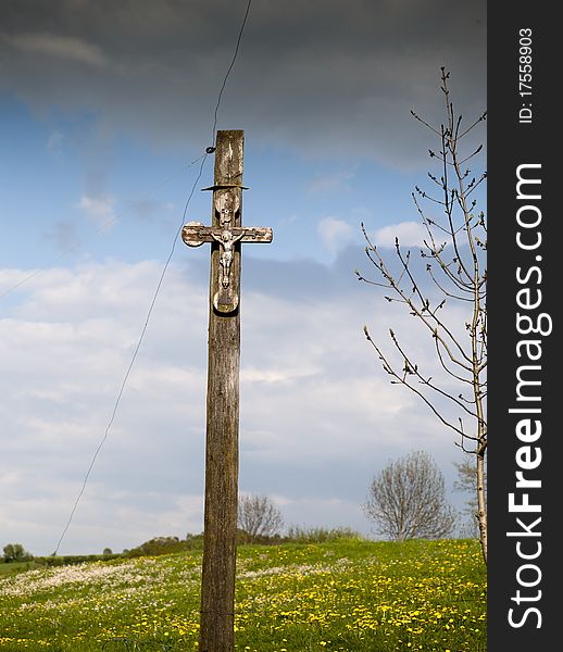 Crucifix in field in the background yellow flowers