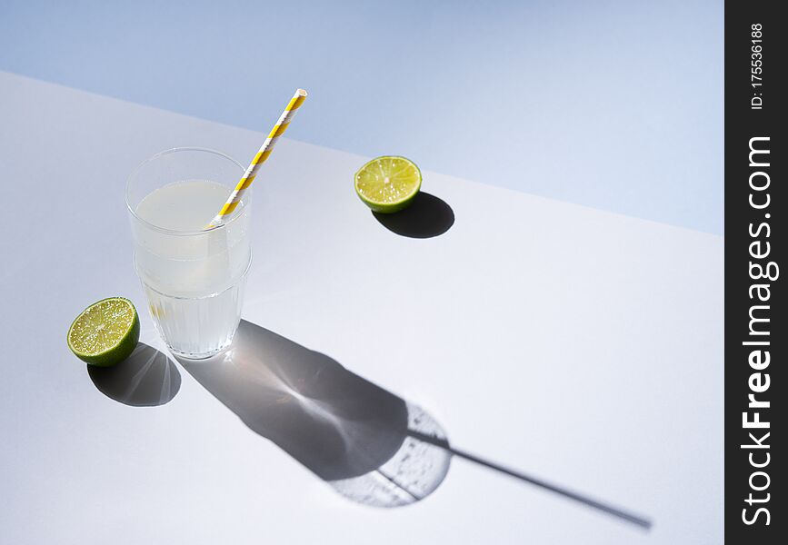 A glass of fresh cold lime lemonade on a gray blue background with hard shadows