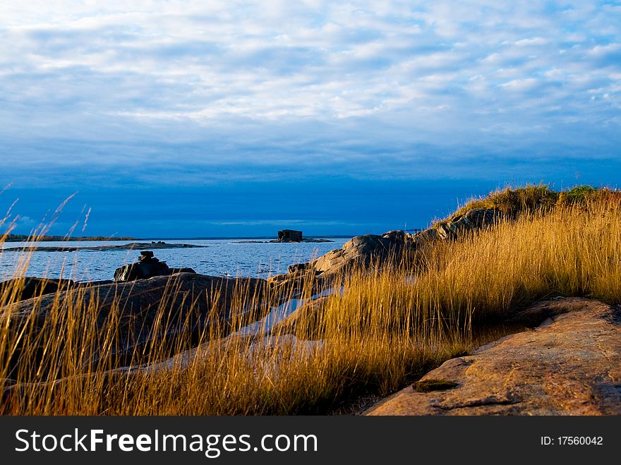 Rock with a yellow grass against the sea and the sky. Rock with a yellow grass against the sea and the sky