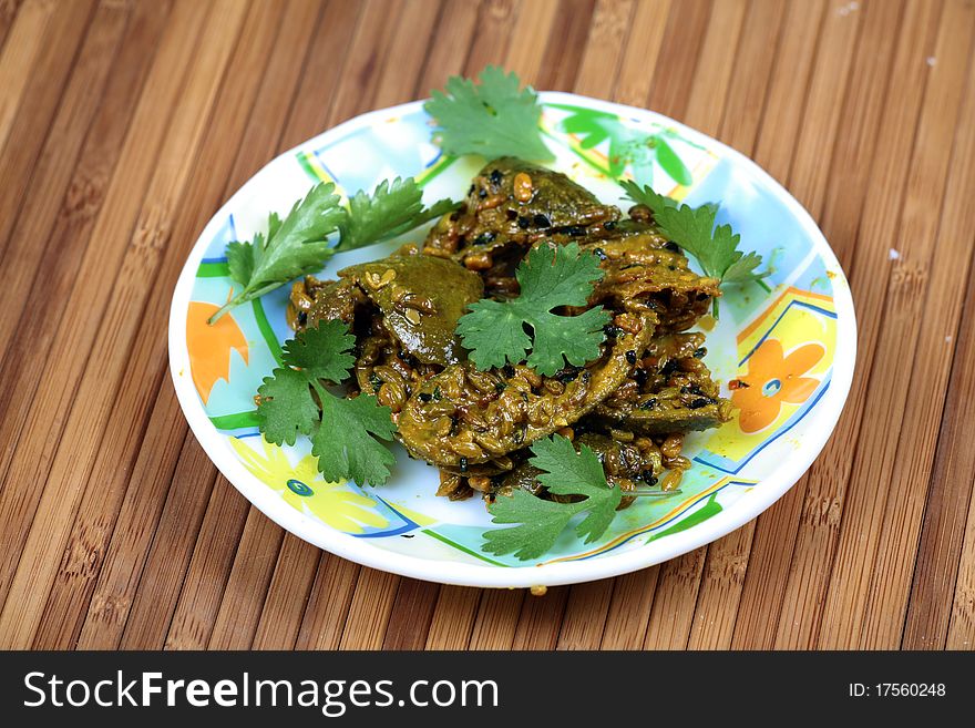 Home-made mango pickle in white plate over wooden background.