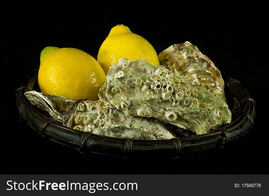 Oysters and lemons in a basket on black background
